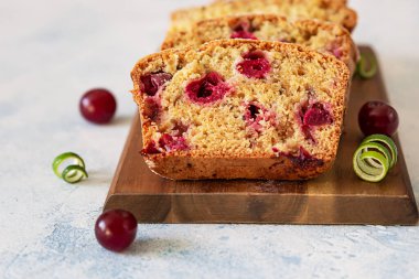 Tahtada kirazlı ve fındıklı ev yapımı kek dilimleri. Açık mavi taş arkaplan.