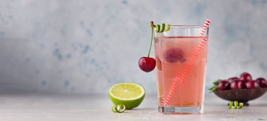 Limonata ya da alkolsüz kokteyl, kiraz ve limonlu gri arka planda. Yaz meyveli içeceği.