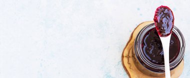 Ev yapımı yabanmersini reçelli kaşık, açık mavi arka plan. Kopyalama alanı olan üst görünüm.