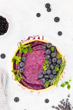 Yabanmersinli cheesecake, sufle veya taze yaban mersinli fırında puding, biberiye ve nane, seçici odak. Lezzetli yaz tatlıları. Hafif beton arka plan. Üst görünüm.