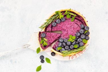 Dilimlenmiş cheesecake veya yaban mersini, nane ve biberiyeli süzme peynir güveci. Seçici odaklanma. Işık taşı arkaplanı.