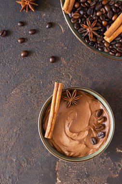Kahve ve çikolatalı puding ya da seramik kasede tarçın ve anason yıldızlı krema, seçici odaklanma. Koyu kahverengi desenli beton arka plan.