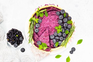 Dilimlenmiş cheesecake veya yaban mersini, nane ve biberiyeli süzme peynir güveci. Seçici odaklanma. Hafif arkaplan.