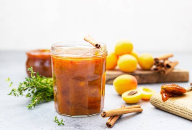 Cam kavanozda kayısı reçeli, taze kayısı, kekik ve tarçın..