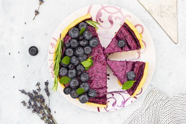 Dilimlenmiş cheesecake veya yaban mersini, nane ve biberiyeli süzme peynir güveci. Seçici odaklanma. Işık taşı arkaplanı.