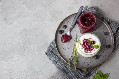 Lezzetli ev yapımı siyah frenk üzümü, krema ya da reçel, yoğurt ve gri beton arka planda taze böğürtlen. Sağlıklı kahvaltı..