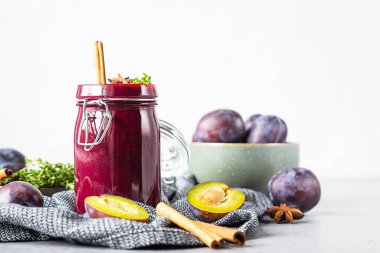 Gri bir masada ev yapımı baharatlı erik reçeli, meyve, kekik ve baharat..