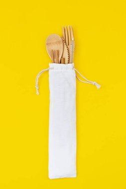 Sarı arka planda bambu ağacından yapılmış tek kullanımlık, çevre dostu aletler. Sıfır atık. Üst görünüm.