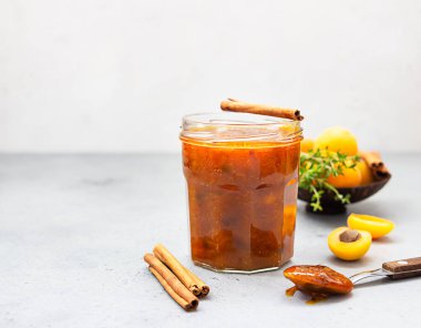 Cam kavanozda kayısı reçeli, taze kayısı, kekik ve tarçın..