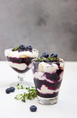 Tiramisu. Yabanmersinli, kremalı, yaban mersinli ve kekikli ev yapımı tatlı. Açık gri arkaplan.