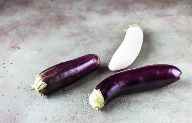 Çiğ mor ve beyaz patlıcan, Solanum melongena veya yeşil taş zemin üzerinde su damlası olan patlıcan..