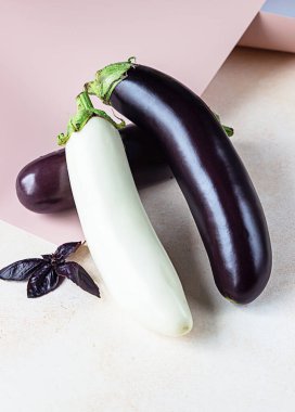 Beton arka planda mor fesleğenli taze beyaz ve mor patlıcanlar..