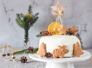 Noel ya da zencefilli kek üzerine zencefilli kurabiye, köknar ağacı dalları, koniler, baharatlar ve kurutulmuş portakal dilimleri ile süslenmiş. Kış pastası. Gri beton arkaplan.
