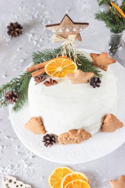 Noel ya da zencefilli kek üzerine zencefilli kurabiye, köknar ağacı dalları, koniler, baharatlar ve kurutulmuş portakal dilimleri ile süslenmiş. Kış pastası. Gri beton arkaplan.