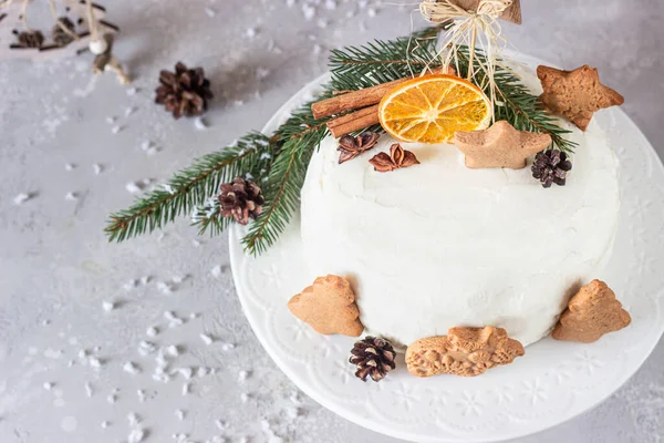 Noel ya da zencefilli kek üzerine zencefilli kurabiye, köknar ağacı dalları, koniler, baharatlar ve kurutulmuş portakal dilimleri ile süslenmiş. Kış pastası. Gri arkaplan.