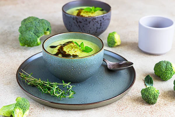Broccoli or spinach green soup with aromatic spicy oil in bowl. Vegan healthy food. Stone background. Selective focus.
