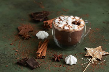 Bir bardak sıcak çikolata ya da marşmelovlu kakao ve anason yıldızı, çikolata, krema ve yeşil arka planda baharatlar. Geleneksel kış içeceği.