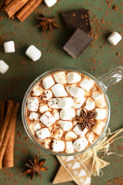 Sıcak kakao ya da çikolatalı marşmelov, anason, tarçın ve çikolata. Seçici odaklanma, yeşil taş arka plan. Sıcak tatil konsepti, Noel ve Yeni Yıl içeceği.