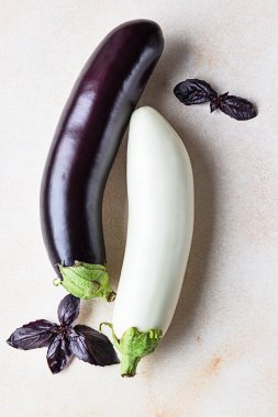 Beton arka planda mor fesleğenli taze beyaz ve mor patlıcanlar..