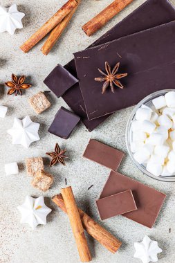Koyu ve sütlü çikolata, tarçın, anason yıldızı, esmer şeker, lokum, krema ve süt. Sıcak çikolata yapmak için gerekli malzemeler. Üst görünüm.