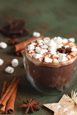 Sıcak kakao ya da çikolatalı marşmelov, anason, tarçın ve çikolata. Seçici odaklanma, yeşil arka plan. Sıcak tatil konsepti, Noel ve Yeni Yıl içeceği.
