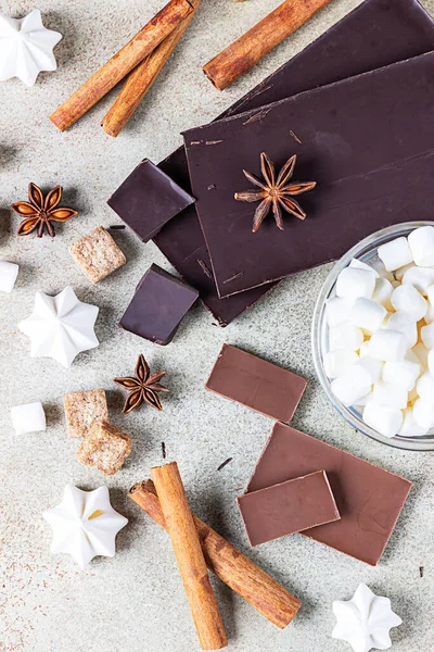 Koyu ve sütlü çikolata, tarçın, anason yıldızı, esmer şeker, lokum, krema ve süt. Sıcak çikolata yapmak için gerekli malzemeler. Üst görünüm.