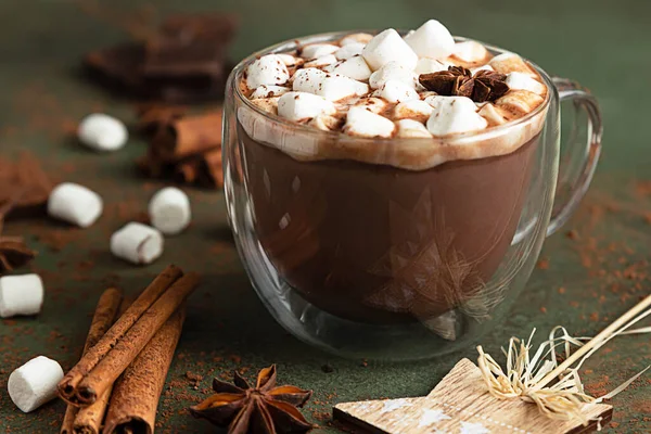 Sıcak kakao ya da çikolatalı marşmelov, anason, tarçın ve çikolata. Seçici odaklanma, yeşil arka plan. Sıcak tatil konsepti, Noel ve Yeni Yıl içeceği.