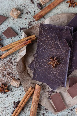 Koyu ve sütlü çikolata parçaları, kakao tozu, tarçın, anason yıldızı ve taş zemin üzerinde esmer şeker. Şekerleme dükkanı reklamcılığı ve yemek malzemeleri konsepti.