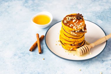 Bir yığın lezzetli kabak kabaklı krep akçaağaç şurubu ya da bal ve fındıklı. Sağlıklı kahvaltı. Sonbahar yemeği. Mavi arkaplan.