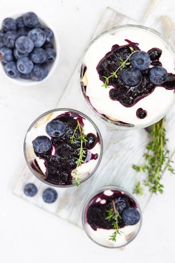 Tiramisu. Yabanmersinli, kremalı, yaban mersinli ve kekikli ev yapımı tatlı. Açık gri taş arkaplan.