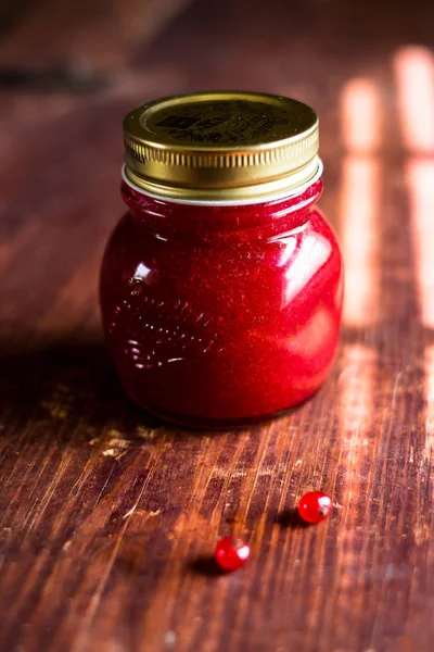 Jar of freshly made red currant jelly jam or sauce on a wooden table, selective focus. Image with copy space. Rustic style.