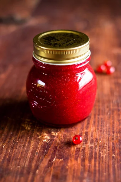 Jar of freshly made red currant jelly jam or sauce on a wooden table, selective focus. Image with copy space. Rustic style.