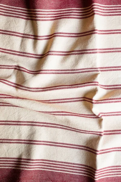 Textile background with a red striped linen napkin, top view. Natural textile background. Fabric texture background. Texture of natural linen fabric.