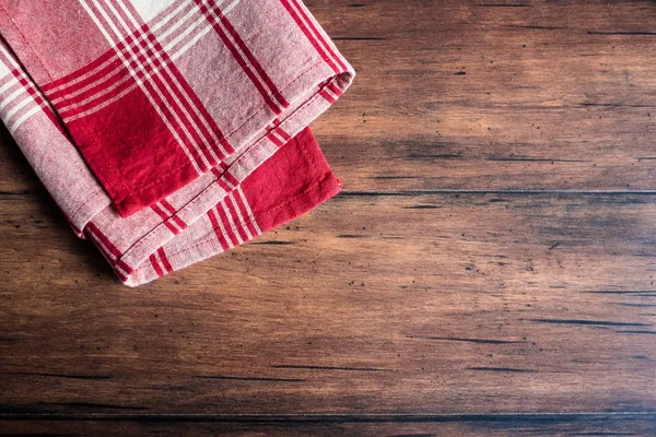 Striped red and white napkin on an old wooden brown background, top view. Image with copy space. Kitchen table with a towel - top view with copy space.