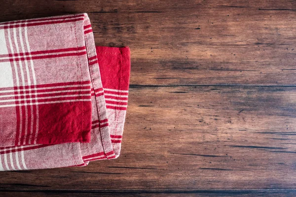 Striped red and white napkin on an old wooden brown background, top view. Image with copy space. Kitchen table with a towel - top view with copy space.