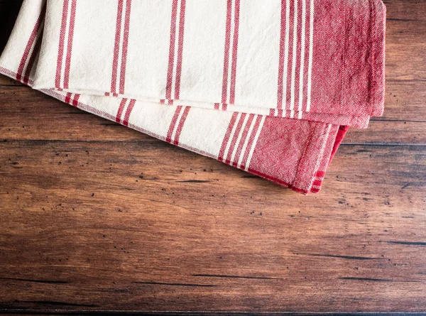 Striped red and white napkin on an old wooden brown background, top view. Image with copy space. Kitchen table with a towel - top view with copy space.