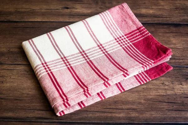 Striped red napkin on an old wooden brown background, selective focus. Image with copy space. Kitchen table with a towel.