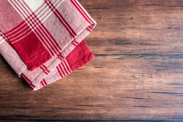 Striped red and white napkin on an old wooden brown background, top view. Image with copy space. Kitchen table with a towel - top view with copy space.