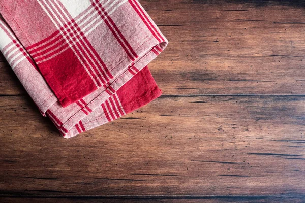 Striped red and white napkin on an old wooden brown background, top view. Image with copy space. Kitchen table with a towel - top view with copy space.