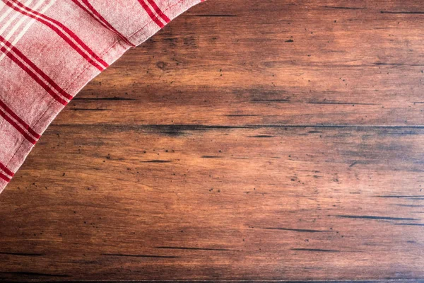 Striped red and white napkin on an old wooden brown background, top view. Image with copy space. Kitchen table with a towel - top view with copy space.