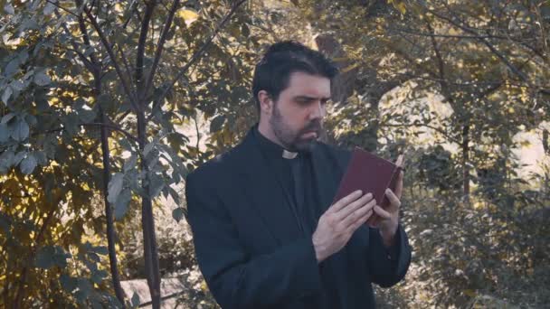 Priester Mit Bibel Tagsüber Draußen — Stockvideo