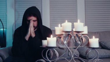 Yanında mumlarla dua eden adam.