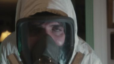 PPE ekipmanlı bir adam kameraya dezenfektan sıkar, salgın hastalık konsepti