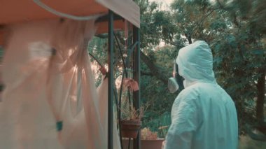 Salgın sırasında PPE takımlı bir adam gündüz evde dolaşıyor.