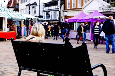 London UK, 03 Ekim 2020, Epsom Marketinde Tek Başına oturan Kadın COVID-19 sırasında izleyen insanlar