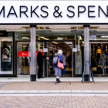 Londra İngiltere 6 Ekim 2020, İnsanlar High Street Perakendecisi 'nin önünden geçiyor ve Spencer, Covid-19' da bazı giyinen yüz kaplamaları yapıyor.