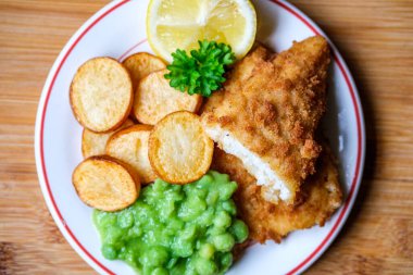 Londra İngiltere, Eylül 03, 2025, Kızarmış patates ve bezelyeli morina filetosu