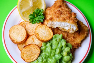 Londra İngiltere, Eylül 03, 2025, Kızarmış patates ve bezelyeli morina filetosu