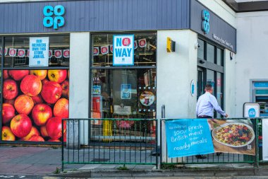 London UK, September 22 2025, Anonymous Man Walking Past The Entrance Of a Co-op Supermarket