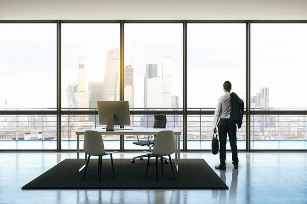 Arkadan Görünüş workdesk duran ve şehir manzaralı pencere bakarak işadamı üzerinde. 